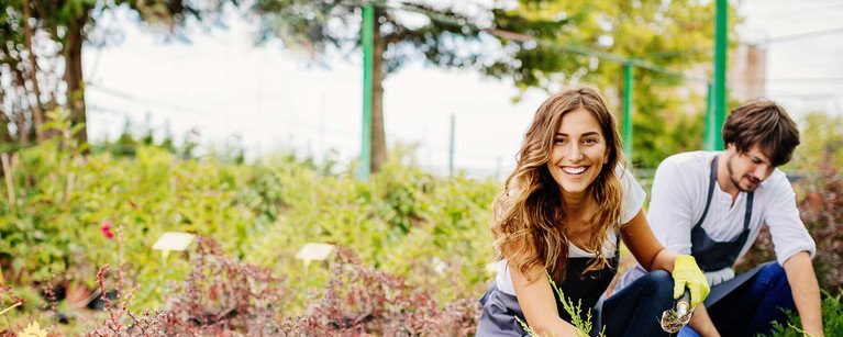 Im Bild ist eine Frau zu erkennen, die glücklich der Gartenarbeit nachgeht